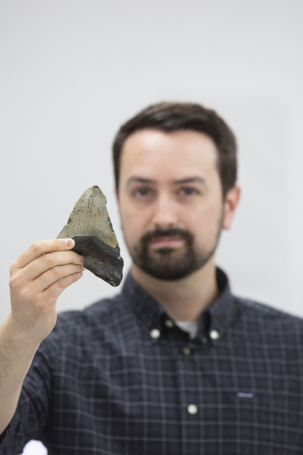 Jeremy McCormack com um dente fossilizado de megalodonte (Otodus megalodon)  Foto: Uwe Dettmar para a Universidade Goethe