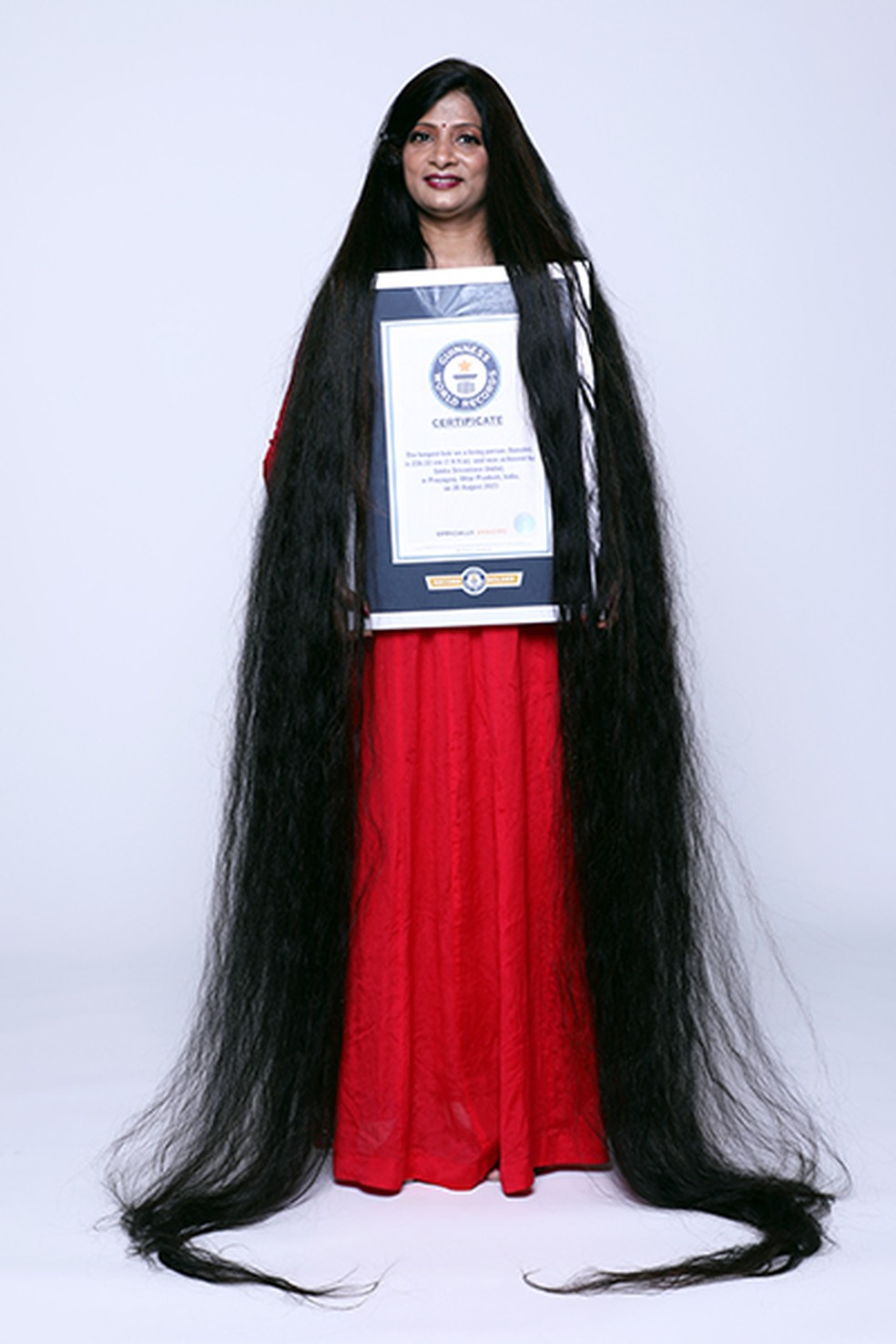 Smita Srivastava segurando seu certificado do Guinness World Records de maior comprimento de cabelo em uma pessoa viva — Foto: Guinness World Records / divulgação