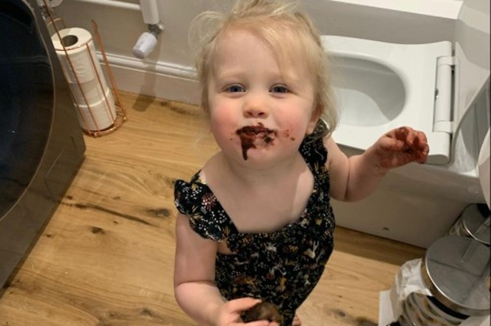 A filha pequena do professor Hoicka, Ada Hersee-Hoicka, de dois anos na foto, escondida no banheiro para comer chocolate — Foto: Elena Hoicka