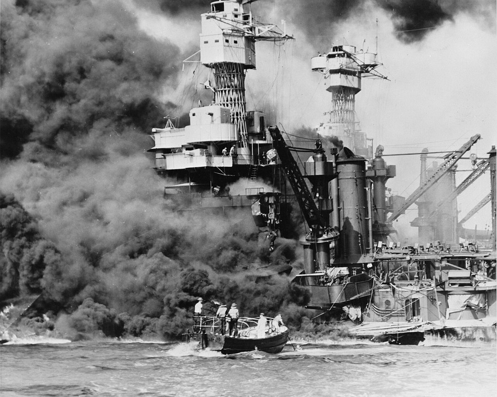 Um pequeno barco resgata um marinheiro do USS West Virginia em chamas, em Pearl Harbor — Foto: Wikimedia Commons