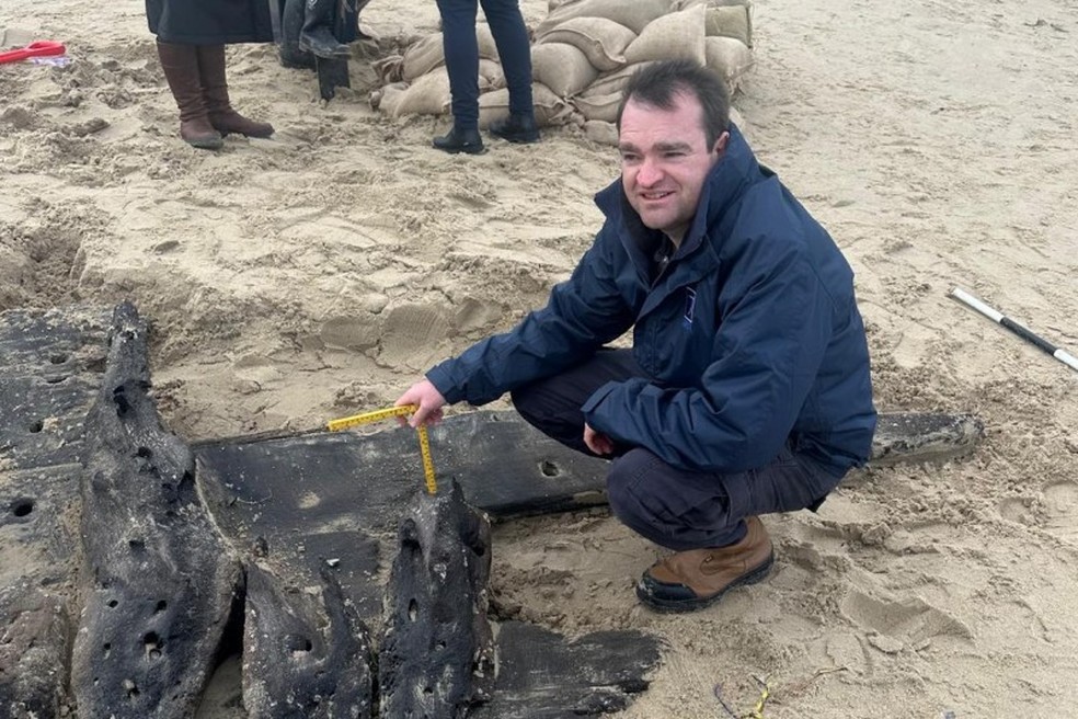 Tom Drupal, arqueólogo marítimo da Universidade de Bornemouth, ao lado de naufrágio do século 17 — Foto: Divulgação