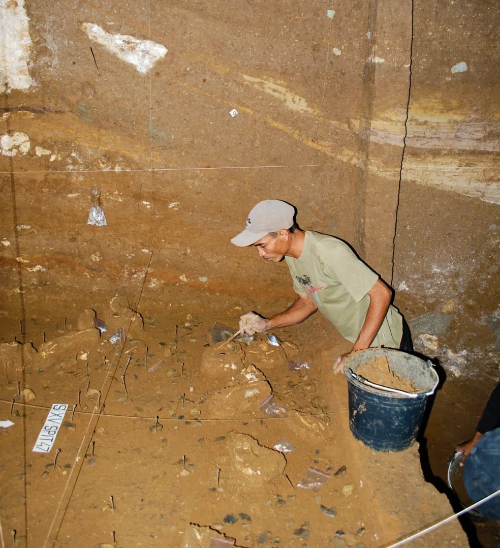 Benyamin Tarus, membro da equipe de escavação, trabalha em depósitos de Homo floresiensis no sítio arqueológico de Liang Bua — Foto: Equipe Liang Bua
