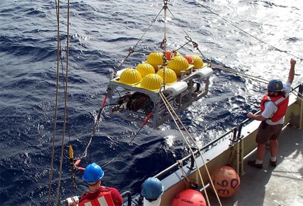 Pesquisadores utilizaram sismógrafos de fundo oceânico, mostrados aqui sendo baixados na água, para estudar o manto terrestre. — Foto: Coleção de Imagens da NASA/Alamy