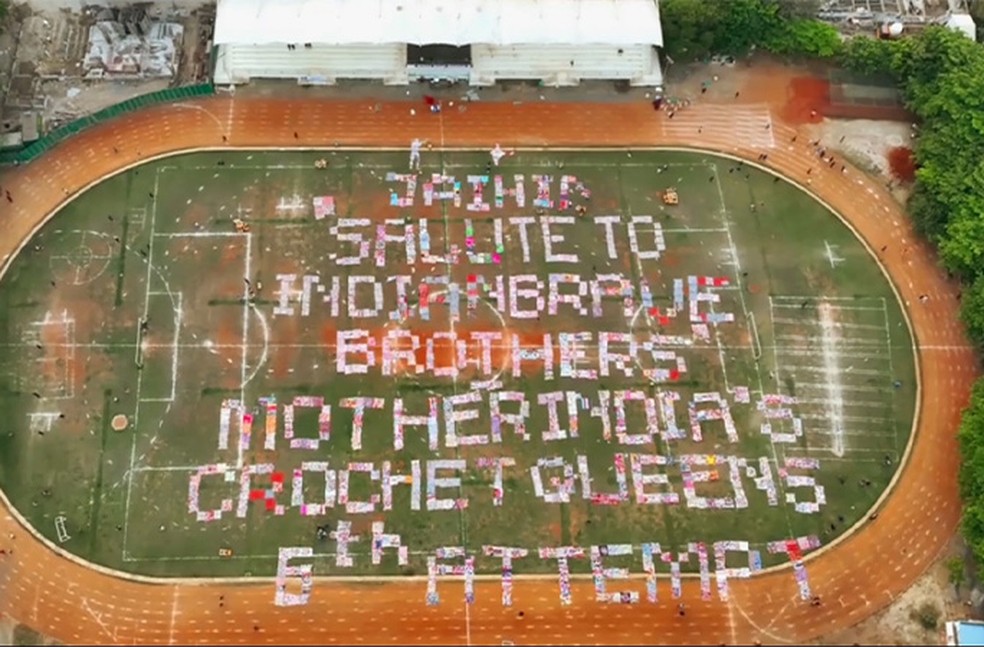 O grupo usou crochê em um campo de futebol para escrever a frase "Jaihind salute to Indian brave brothers, Mother India’s crochet queen's eth attempt", que em tradução significa: "Saudação Jaihind aos irmãos corajosos da Índia, a enésima tentativa da rainha do crochê da Mãe Índia". — Foto: Guinness World Records