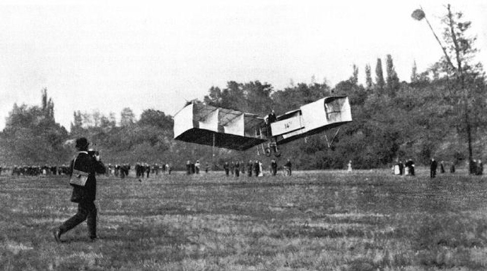 Imagem do momento em que o 14-bis sai do chão, sendo pilotado por Dumont em 23 de outubro de 1906 — Foto: wikimedia commons