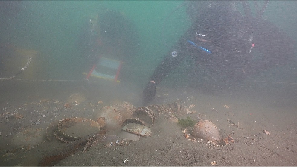 Arqueólogos analisam uma pilha de cerâmica celadon parcialmente soterrada nos sedimentos — Foto: Yonhap