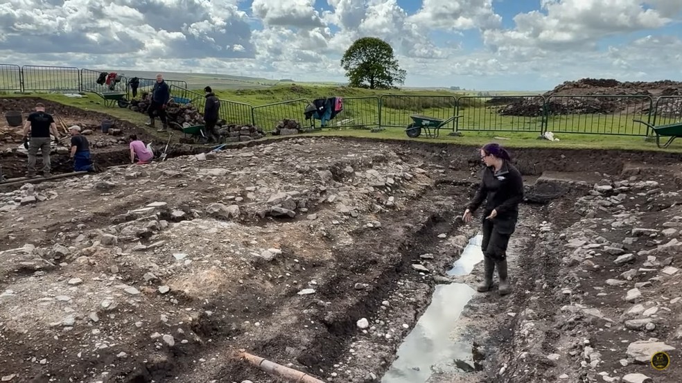 A arqueóloga sênior Rachel Frame ao lado de uma vala “quebra-tornozelos” analisada — Foto: Reprodução/YouTube (VindolandaTrust)