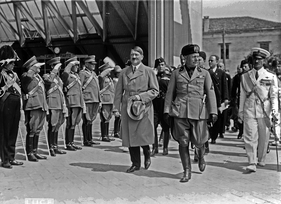 Adolf Hitler e Benito Mussolini caminhando em frente a militares que prestam continência durante a visita de Hitler a Veneza — Foto: Wikimedia Commons