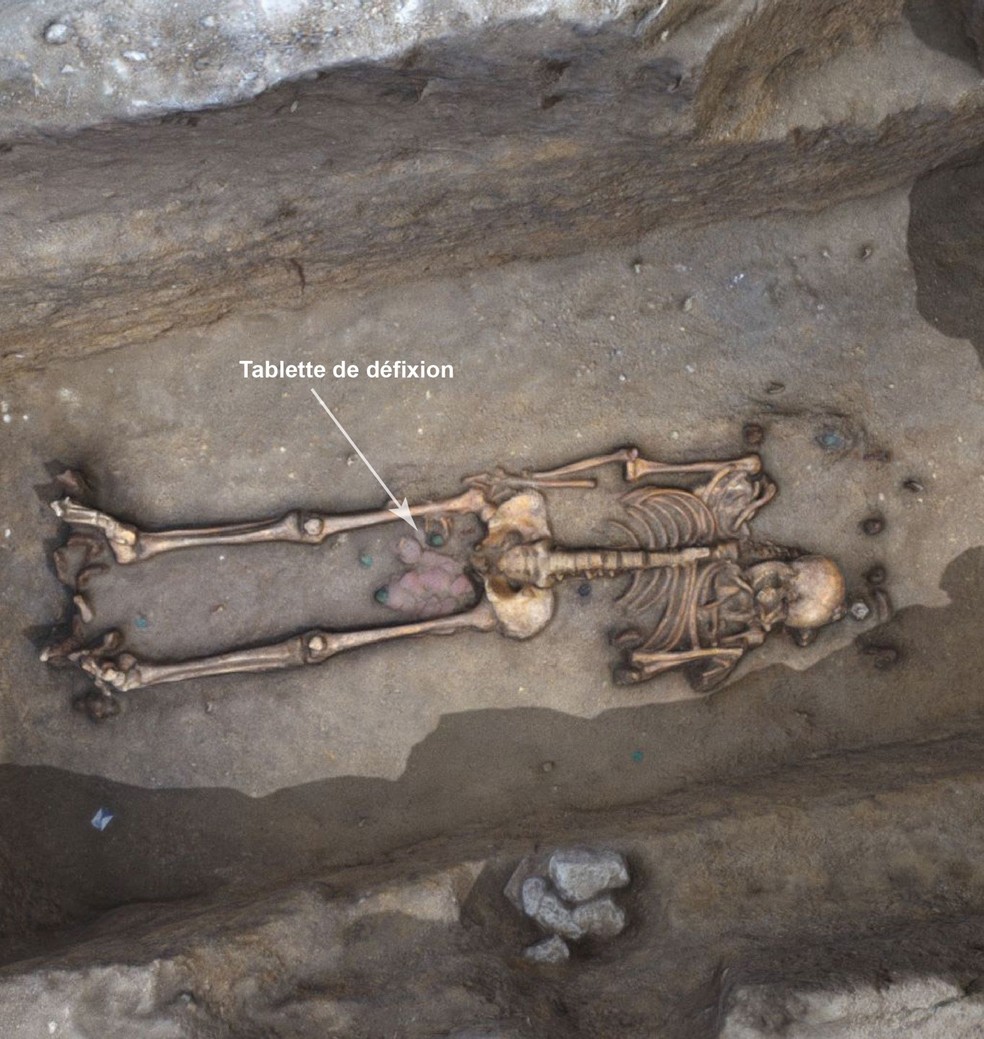 Tábua com escrito em gaulês foi encontrada dentro de túmulo perto das pernas de um homem, um vaso quebrado e moedas — Foto: Serviço Arqueológico de Orléans