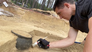 Um pesquisador escava uma urna de cremação encontrada no parque paisagístico Wda — Foto: Wdecki Park Krajobrazowy